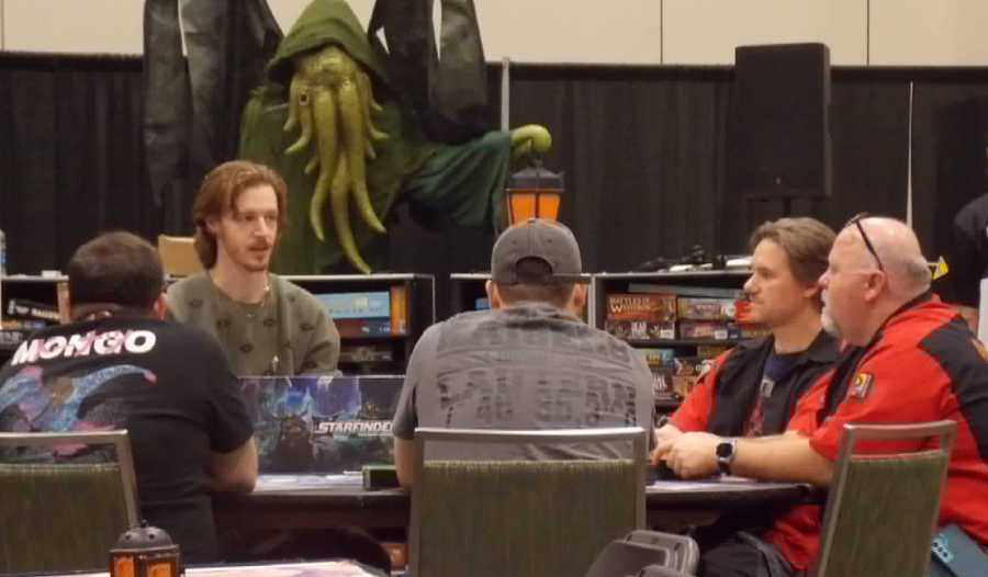 four men sitting at a round table learning to play the roleplaying game Starfinder